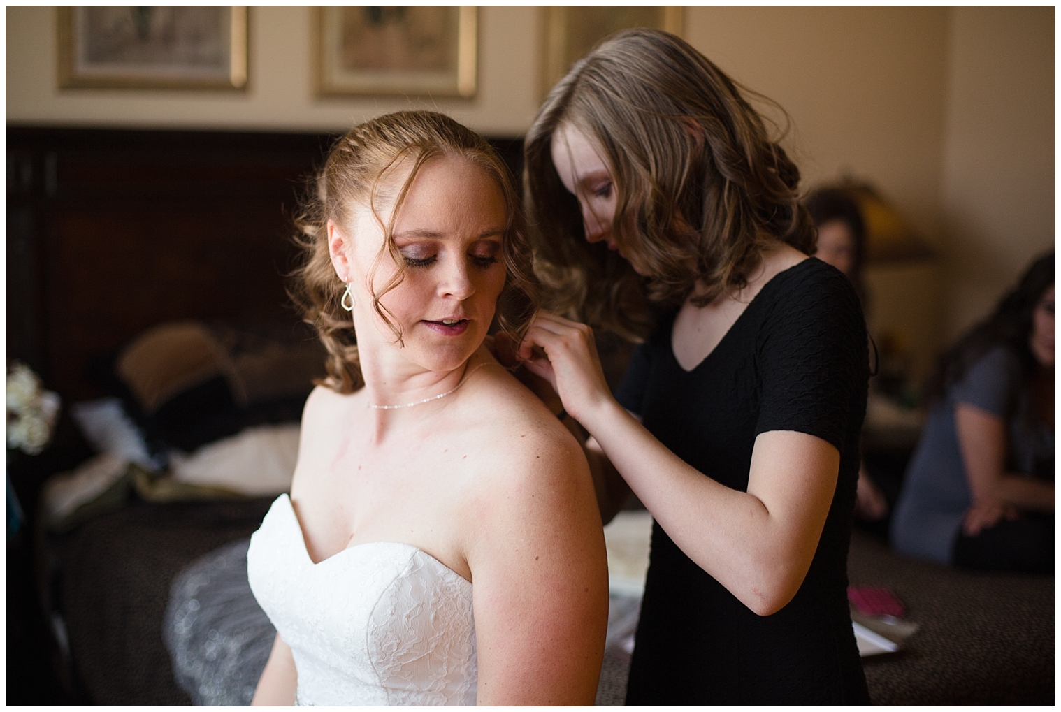 Woman helps the bride put on her necklace while getting ready for a Breckenridge elopement.