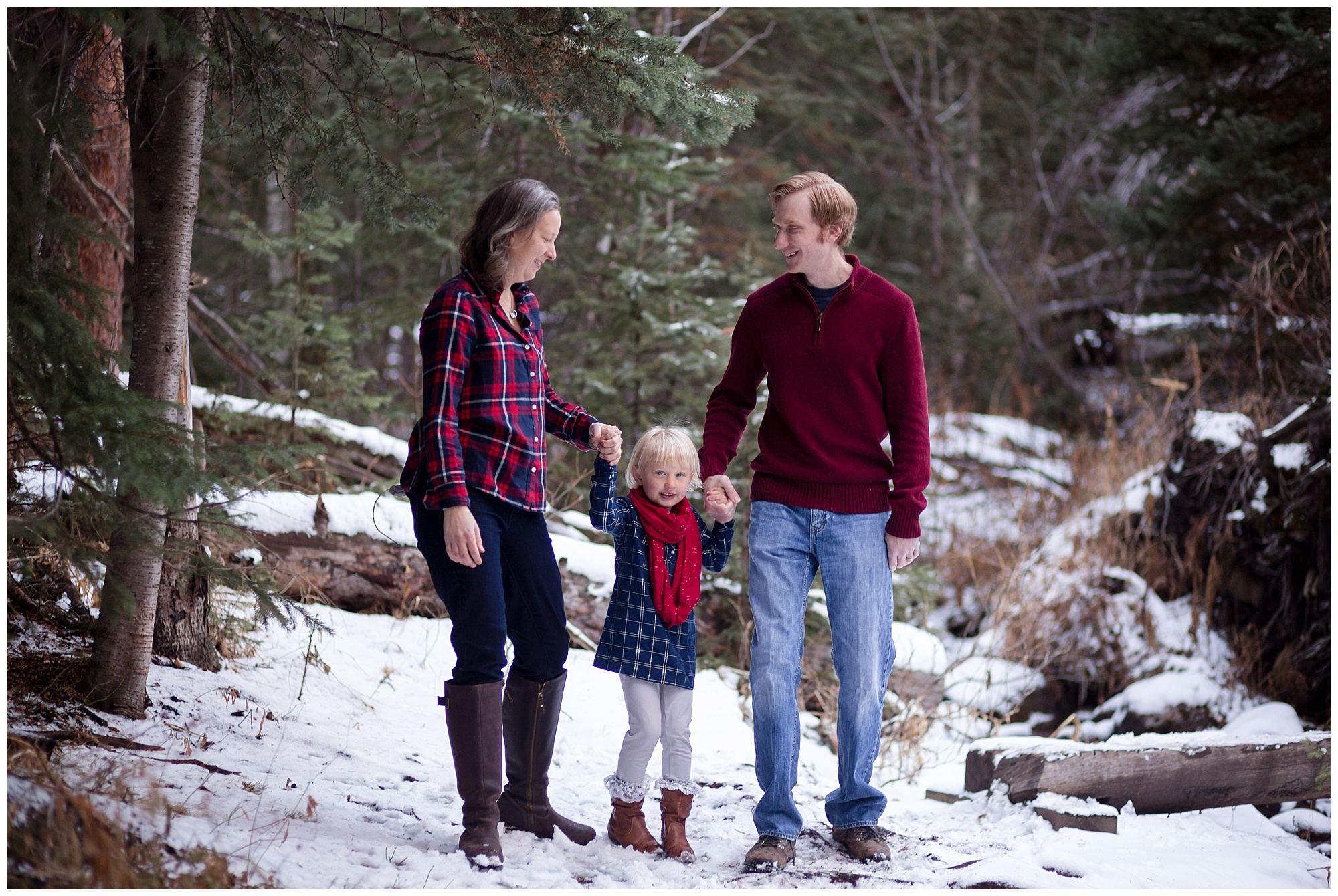 Mom and dad hold their daughter's hands during their session with a Breckenridge family photographer.