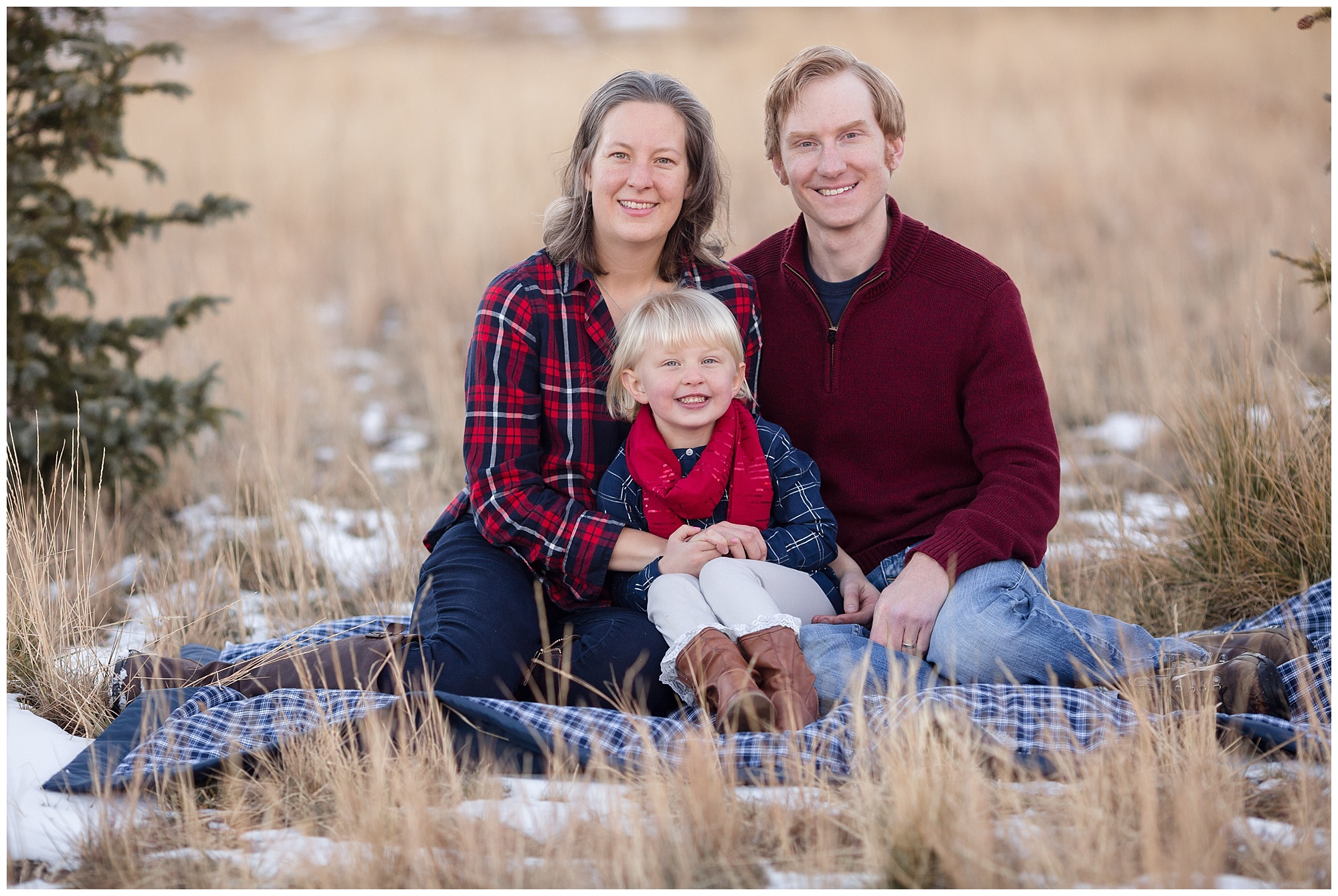 Family sits together on a blanket during their winter family photos.