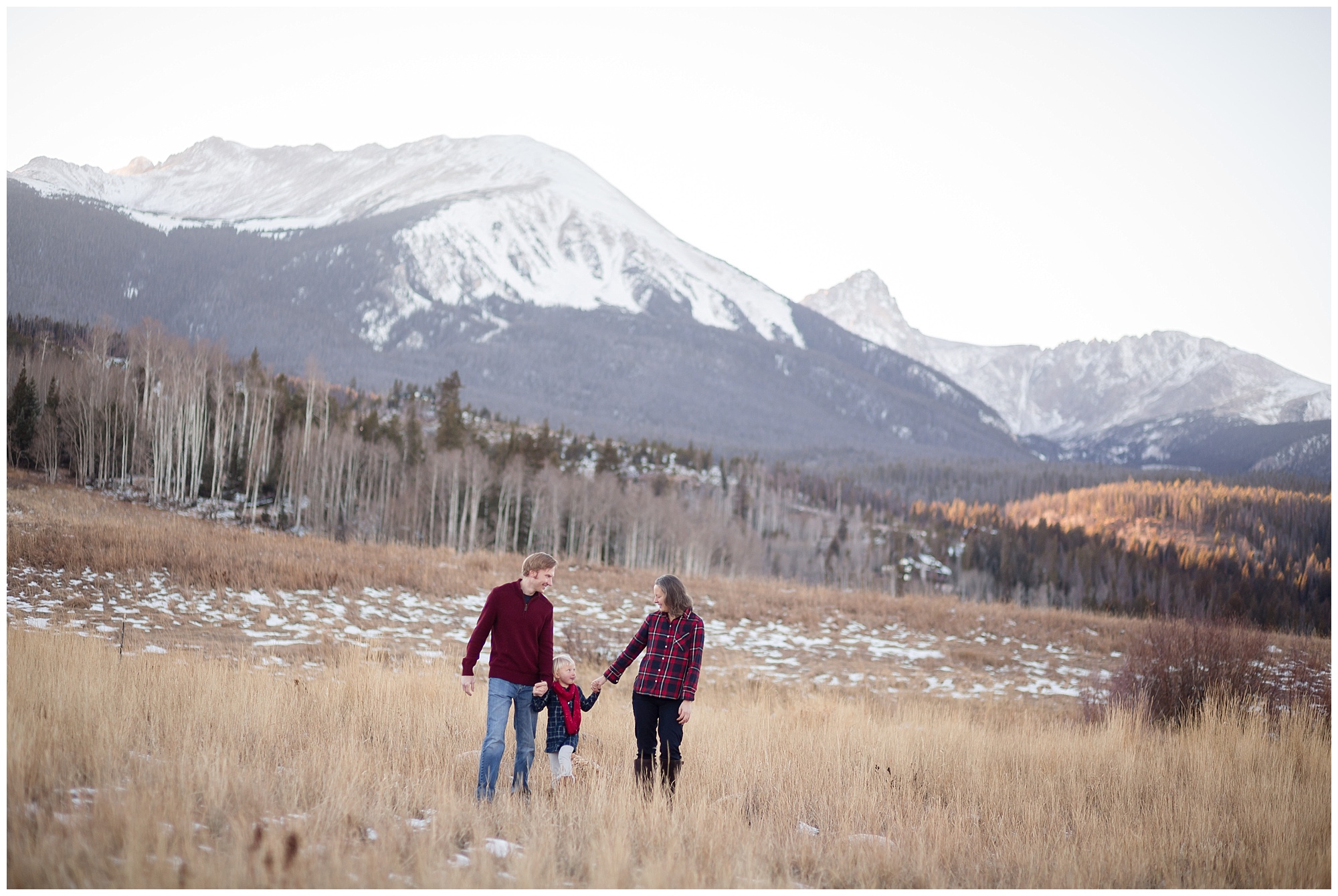 Mom and dad hold their daughter's hands at a Colorado mountain family photography session.