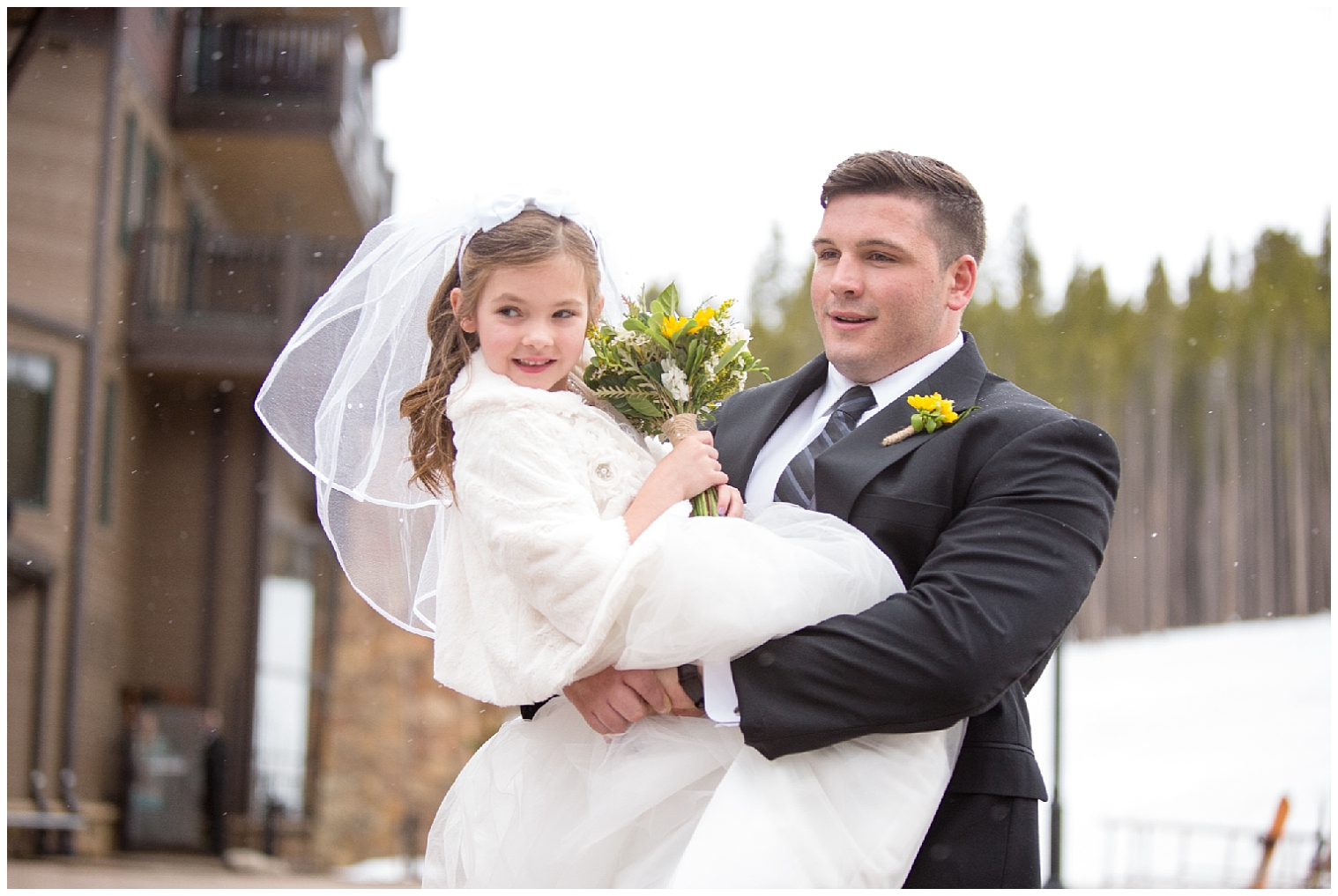 The flower girl is carried down the aisle by a groomsmen at a Breckenridge Colorado wedding.