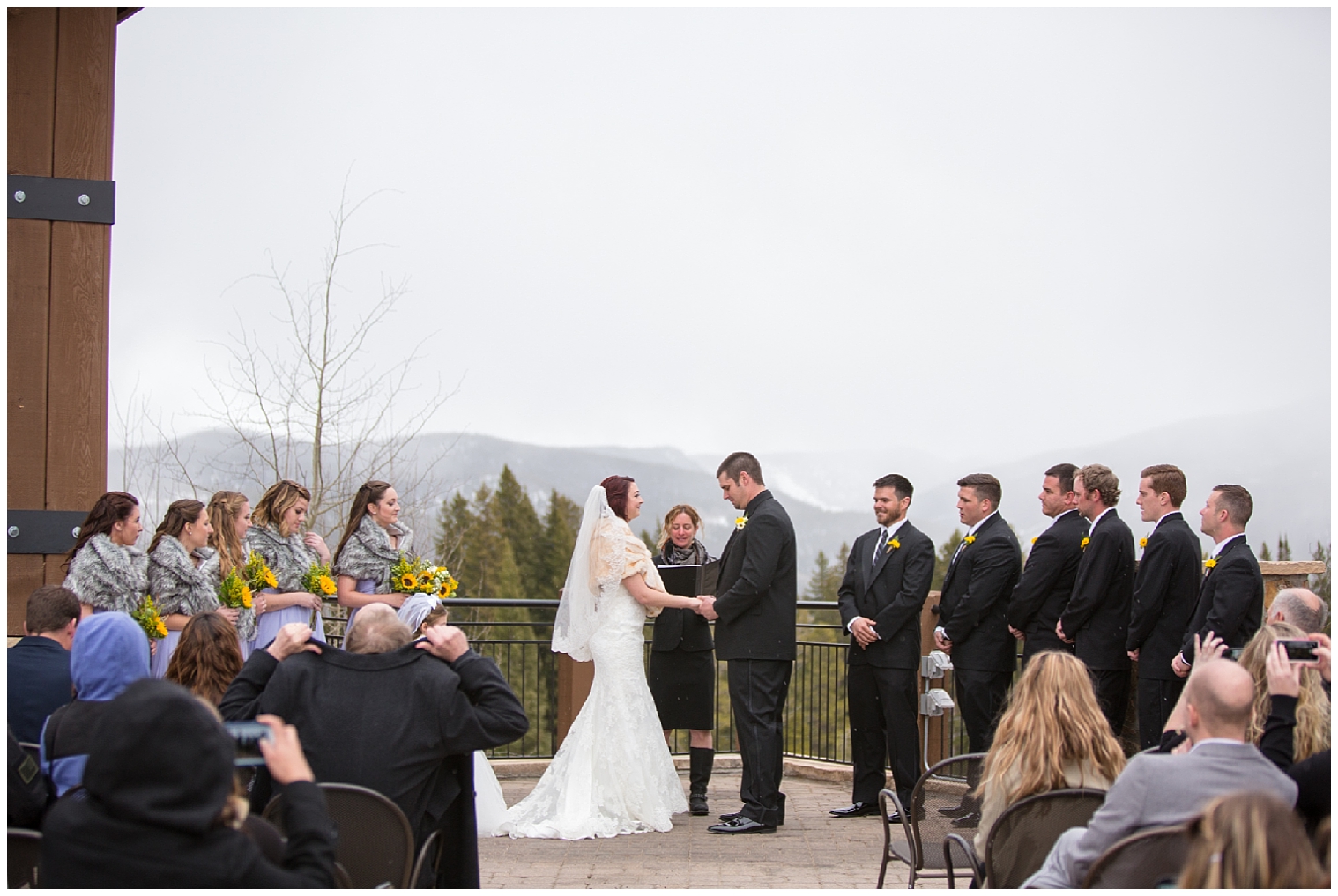 The wedding couple hold hands at the altar at a winter Colorado mountain wedding.