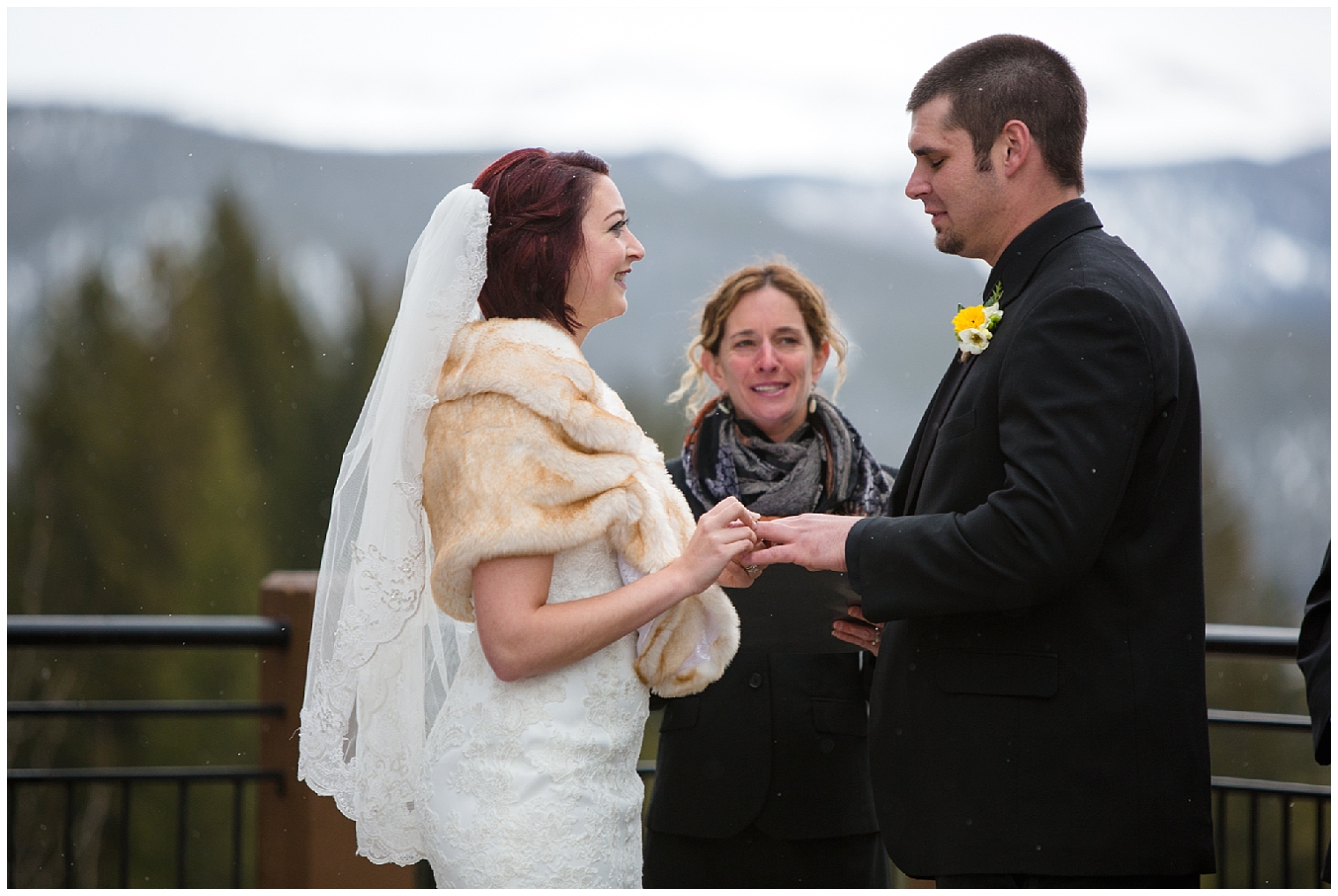 Bride places the ring on the groom during their Colorado mountain wedding ceremony.