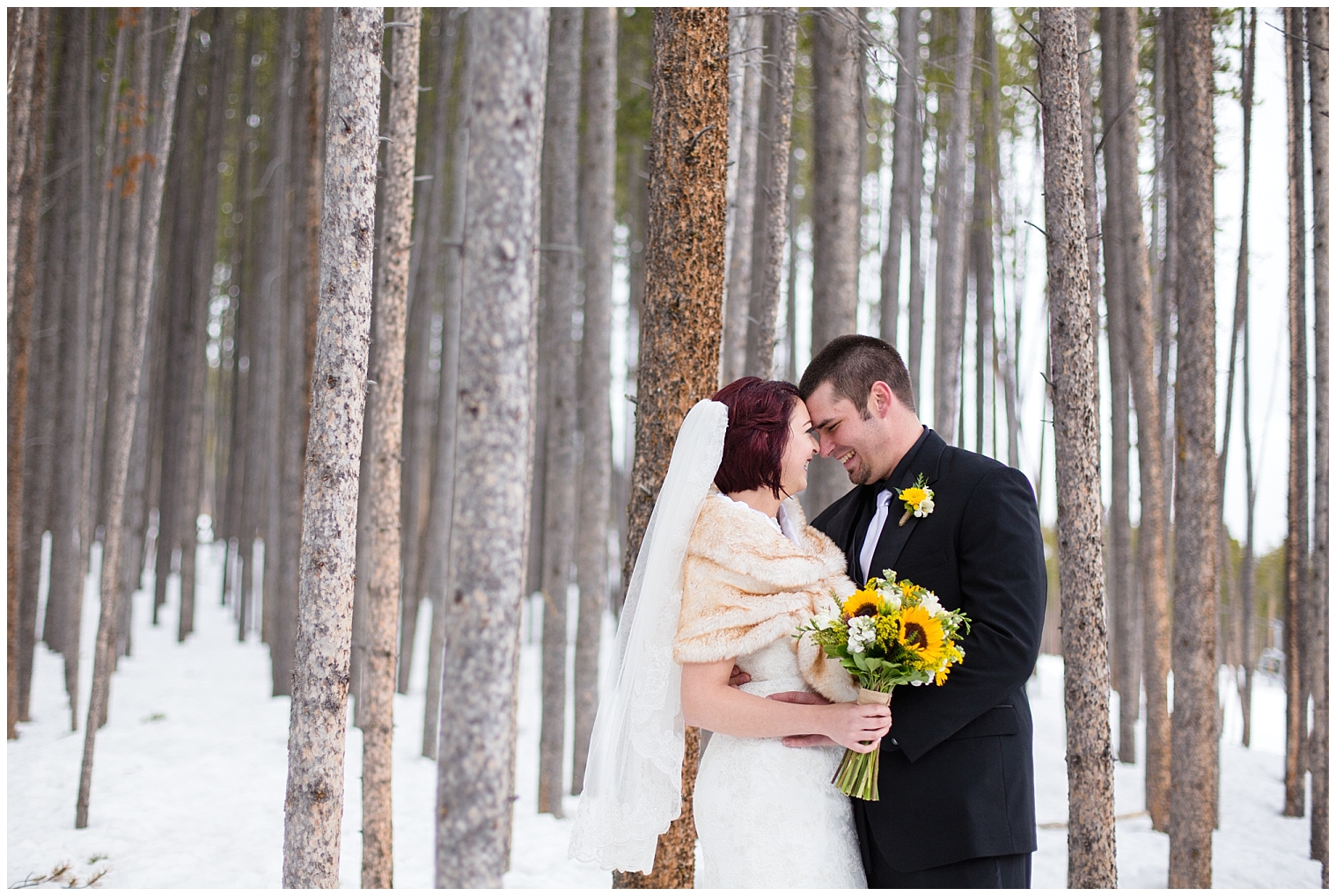 The bride and groom stand together in the trees at their Colorado winter wedding.