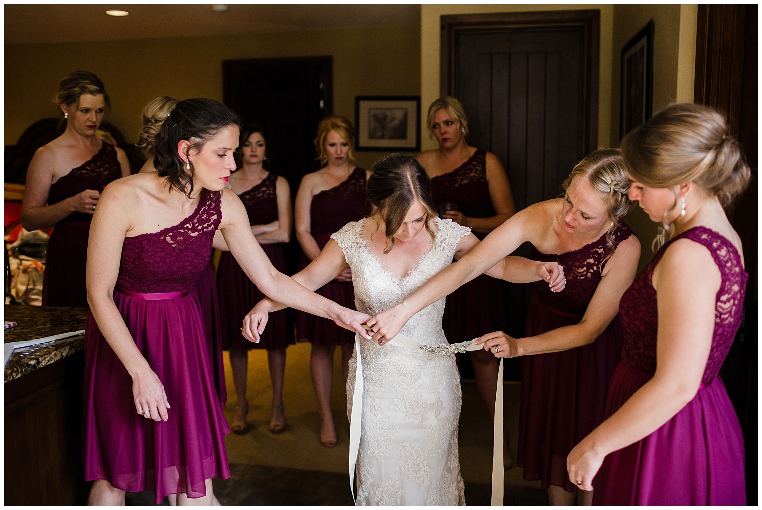 Bridesmaids help tie on brides belt as she gets ready for her Colorado mountain wedding.