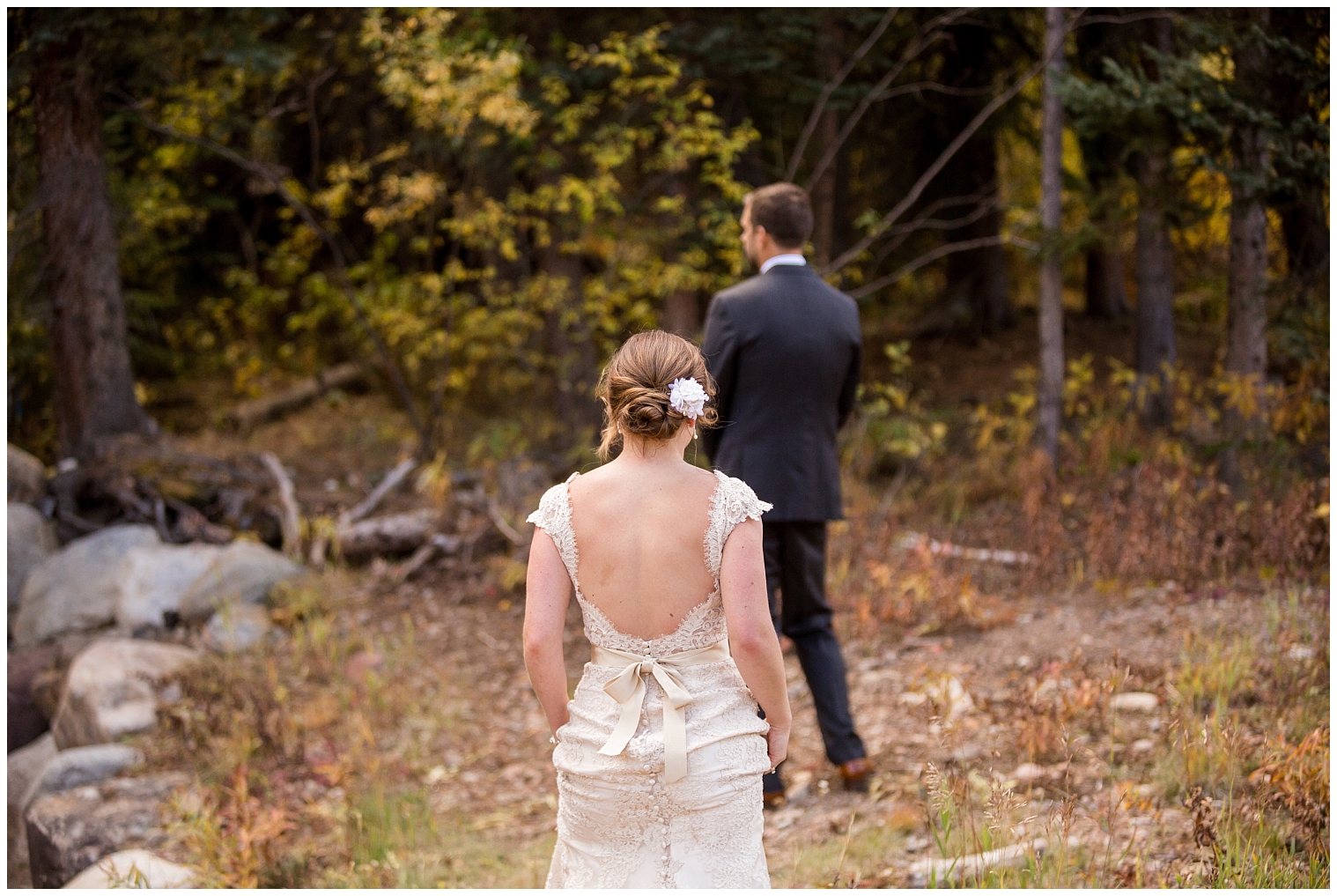 At their Colorado mountain wedding, the bride approaches her groom for their first look.