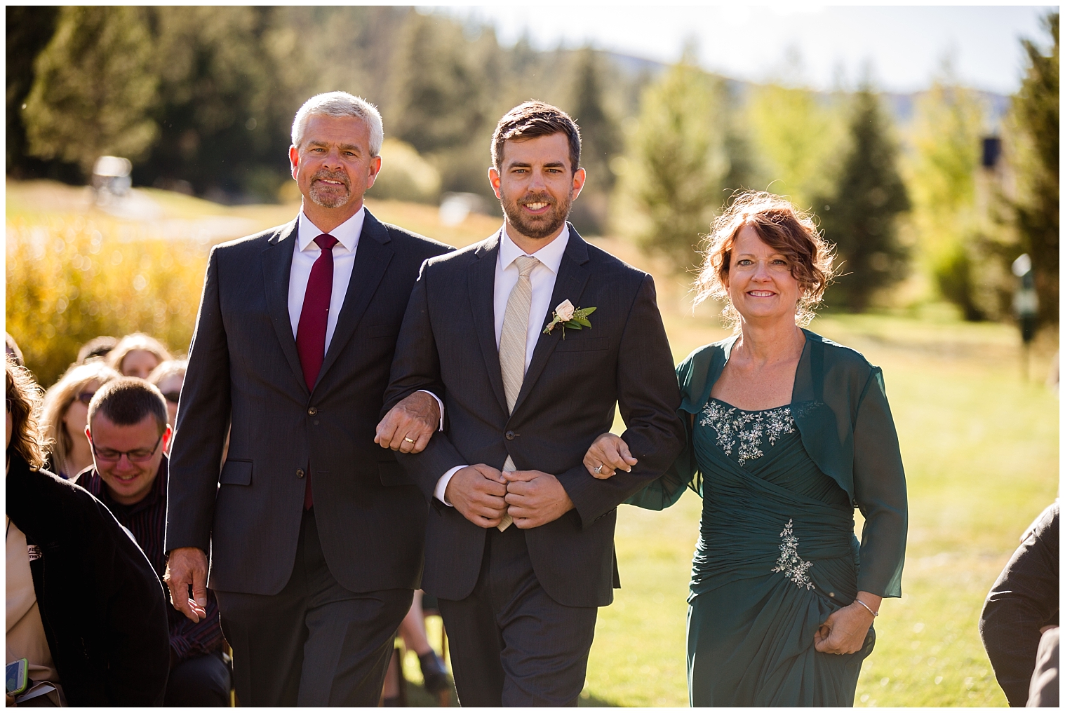 During his Copper Mountain wedding ceremony, the groom walks down the aisle with his parents.