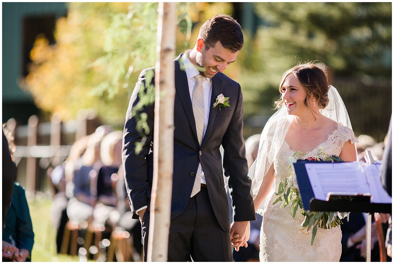The wedding couple hold hands and laugh together during their Copper Mountain wedding ceremony.