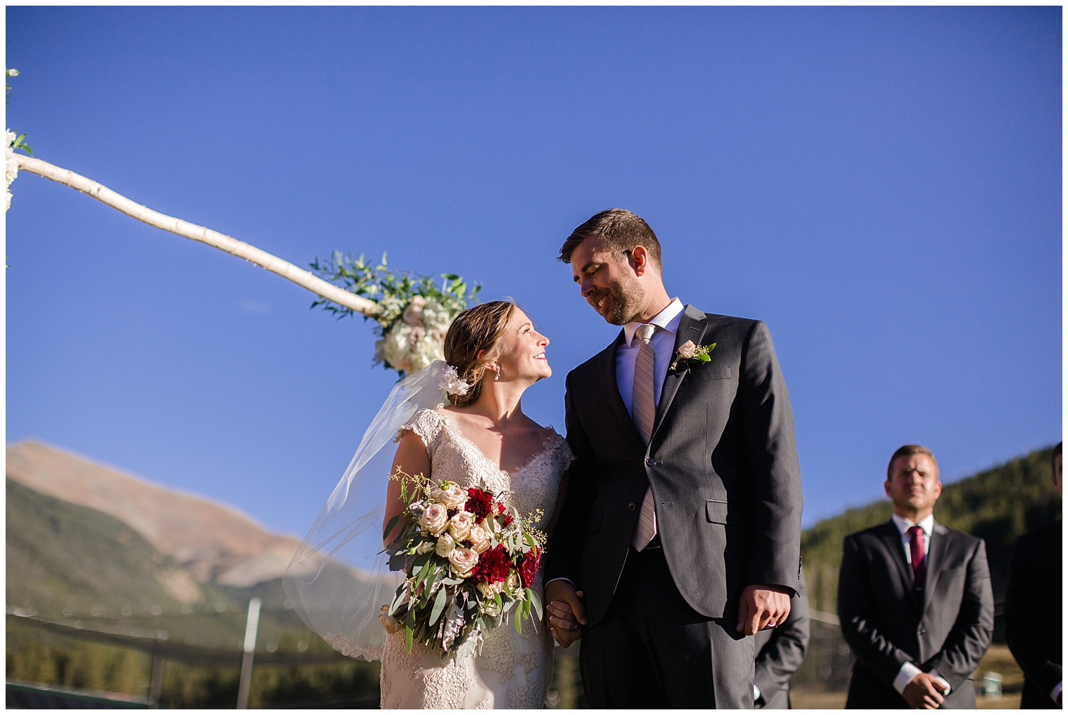 During their Copper Mountain wedding ceremony, the bride and groom hold hands and smile at each other.