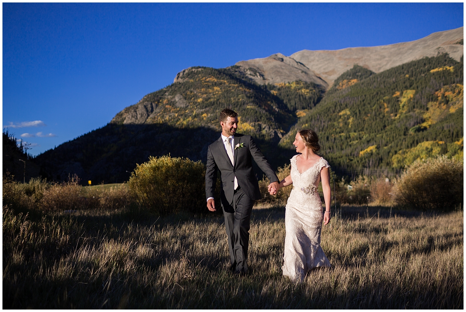 The bride and groom walk hand in hand during their Copper Mountain wedding portraits.