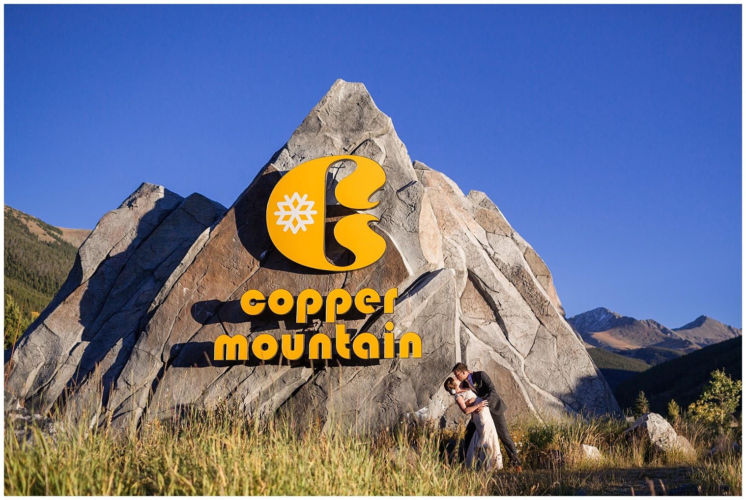 The wedding couple kiss in front of the Copper Mountain sign.