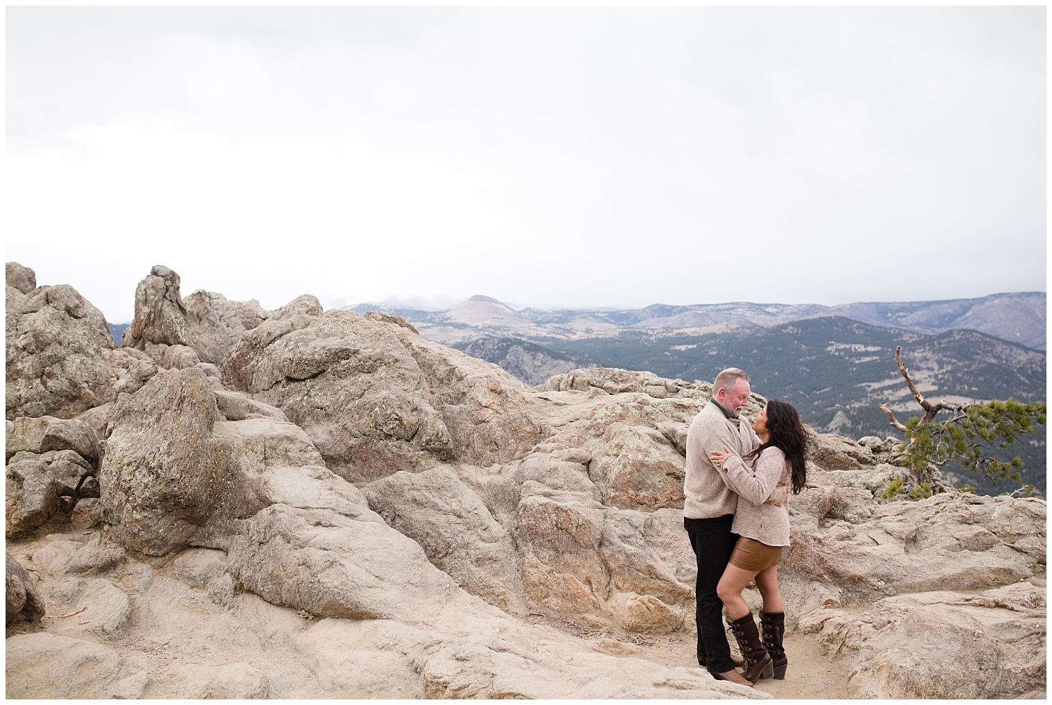 Couple stands on a rocky outcropping during their Colorado mountain engagement photography session.