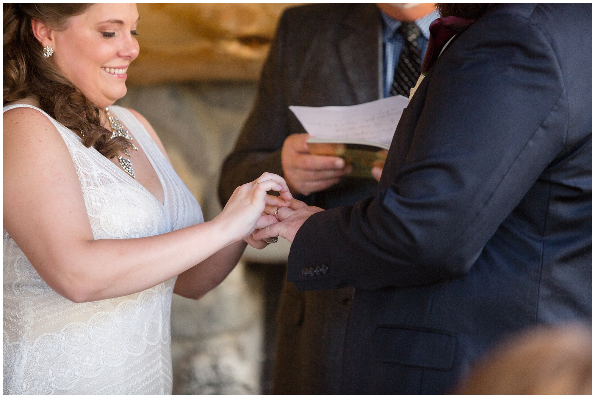 Bride places a ring on her groom's finger during their intimate breckenridge cabin wedding ceremony.