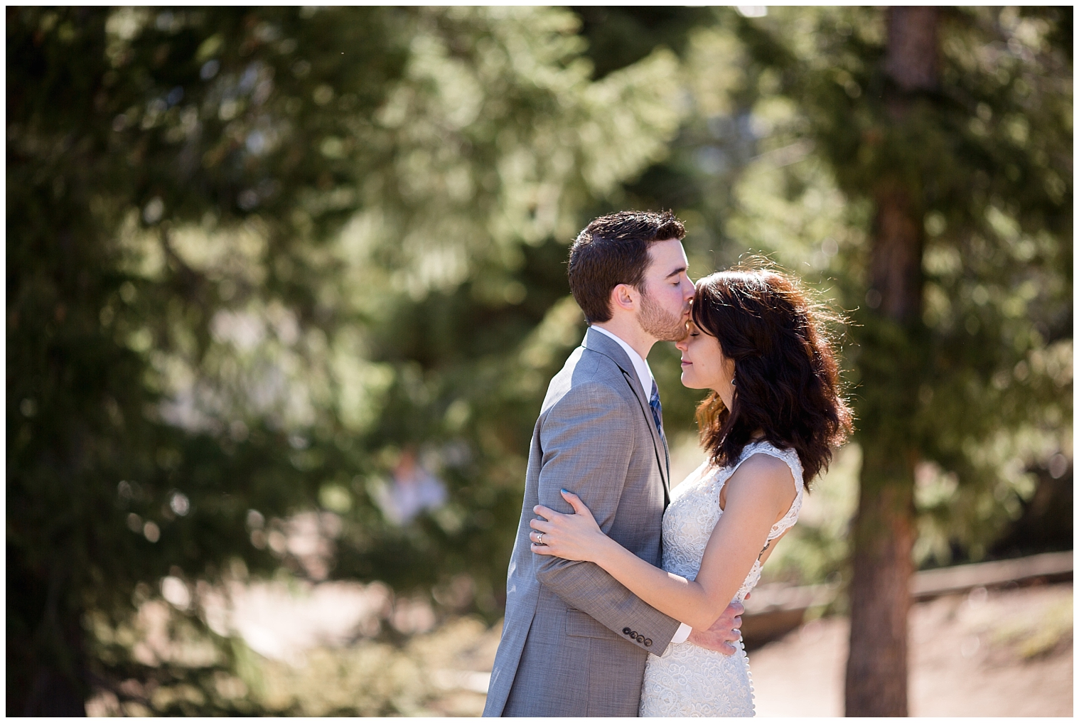 During their Colorado mountain wedding day, the groom kisses his bride's forehead.