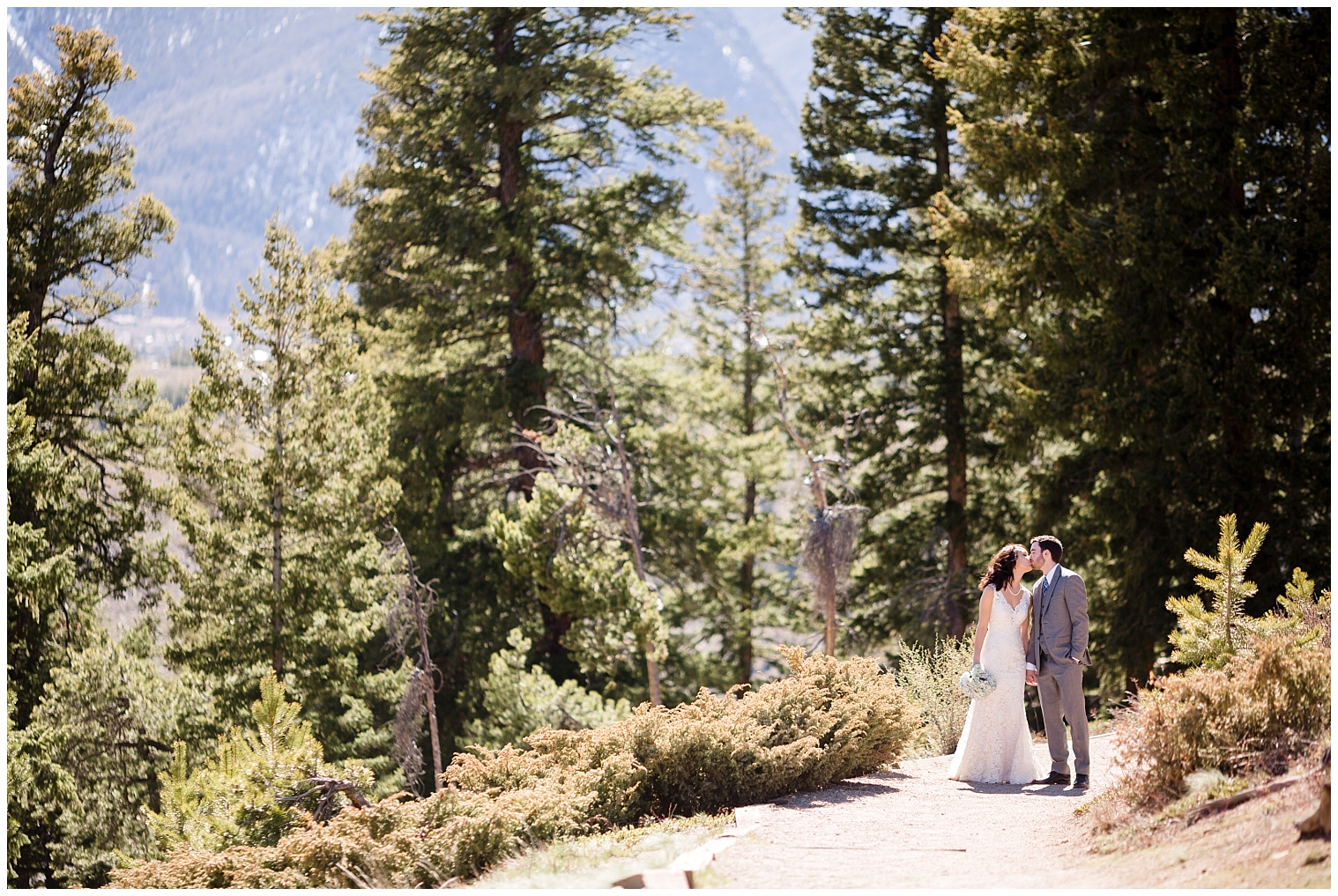 The wedding couple kiss while walking down a path at their Breckenridge elopement.