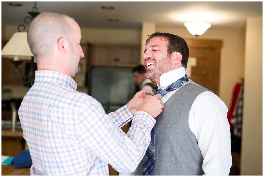 Groomsman helps to tie the groom's tie prior to a Breckenridge wedding.