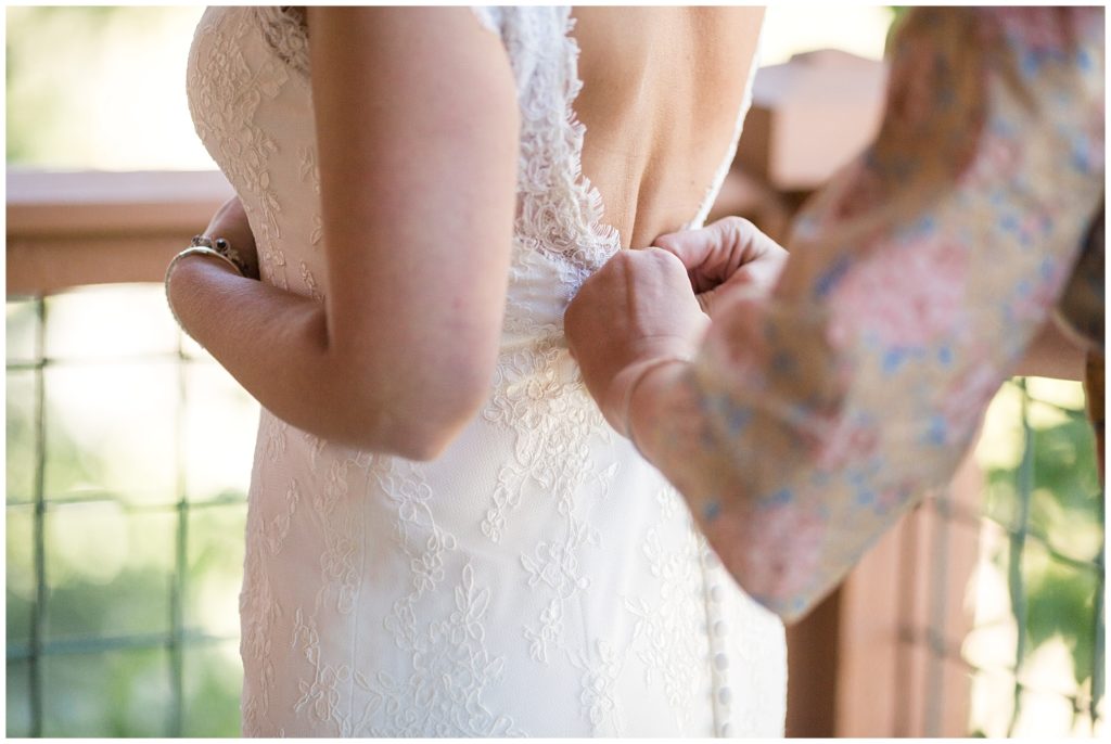 Someone helps button up the bride's wedding dress on her Breckenridge wedding day.