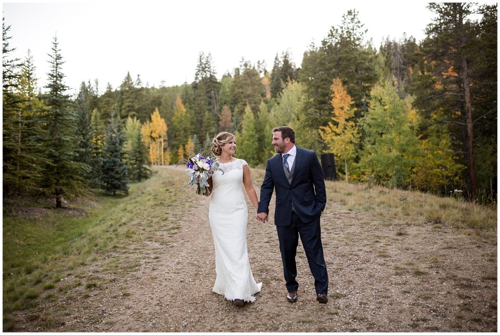 Photo of couple holding hands and walking by a Colorado mountain wedding photographer