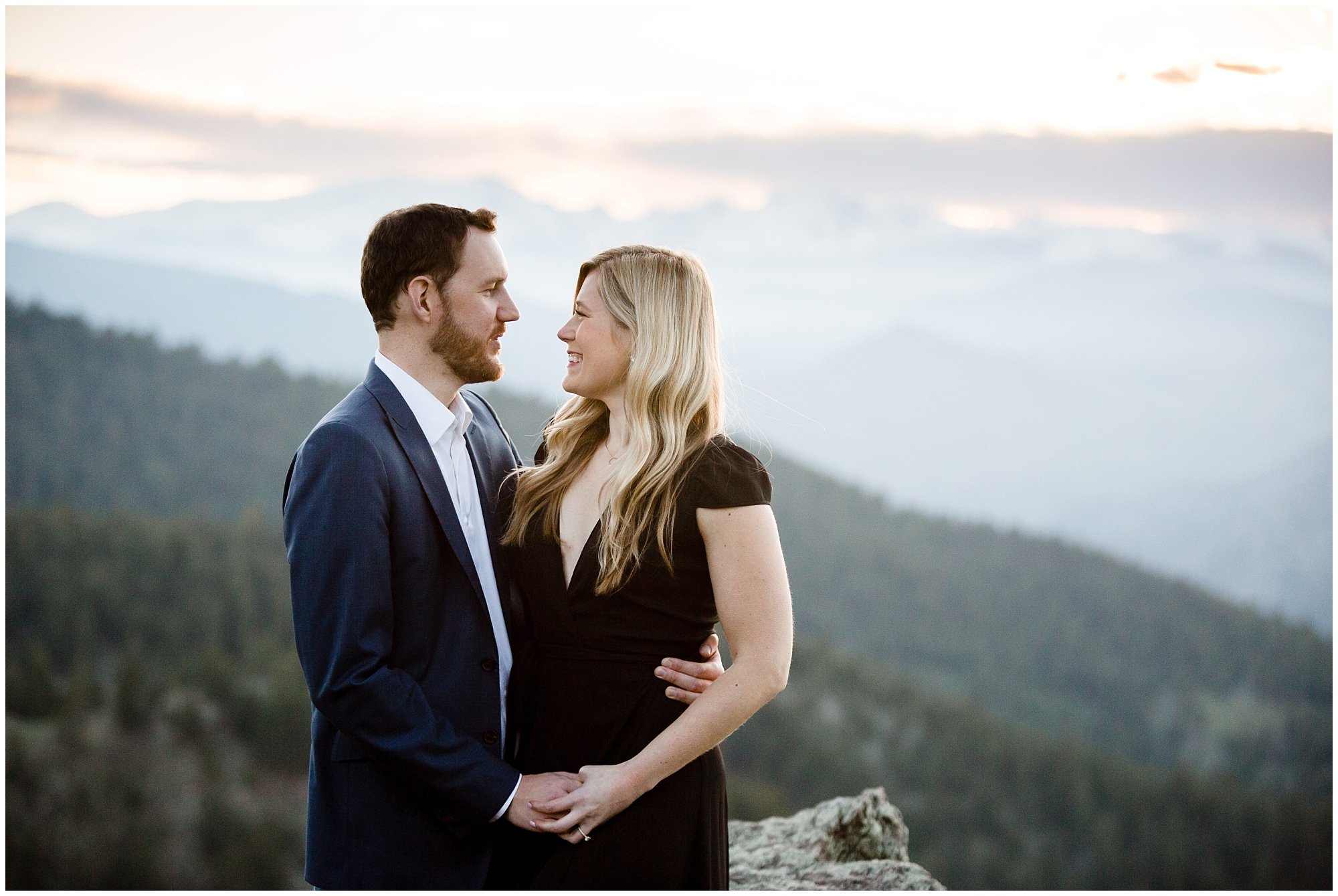 Couple holds each other with mountain views behind them at a Boulder engagement photography session.