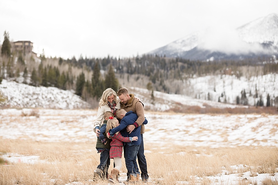 beautiful family hugging in with winter mountain backdrop in Colorado