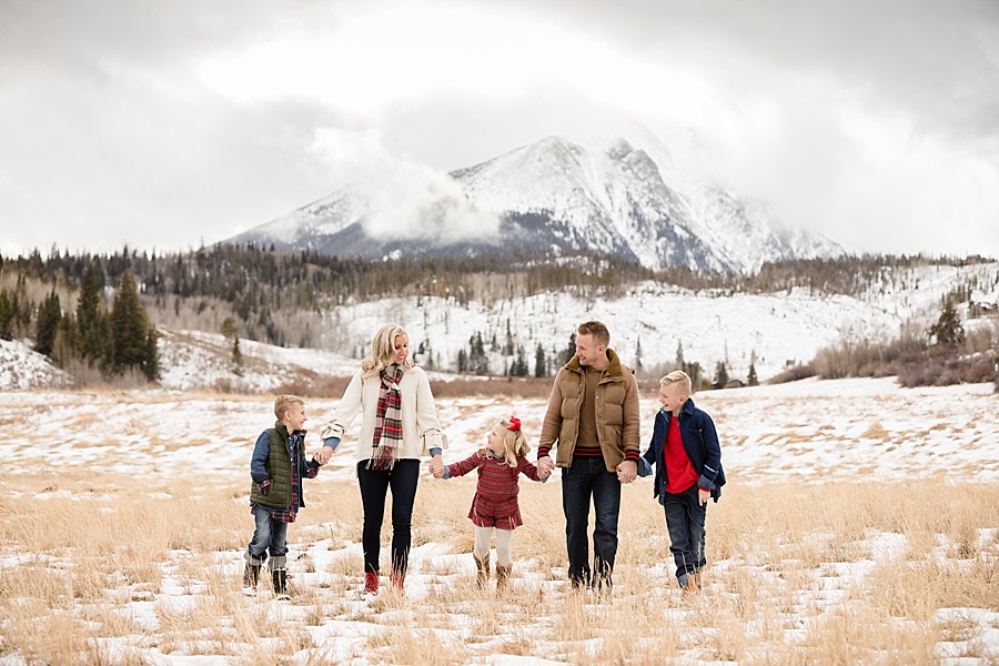 family walking together in front of stunning Colorado mountains in winter