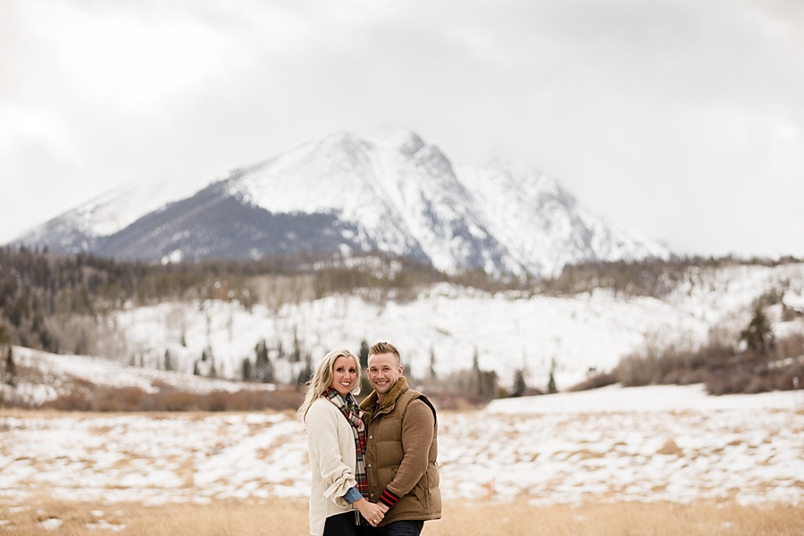 beautiful husband and wife couple pose in front of snowy mountains in Breckenridge Colorado
