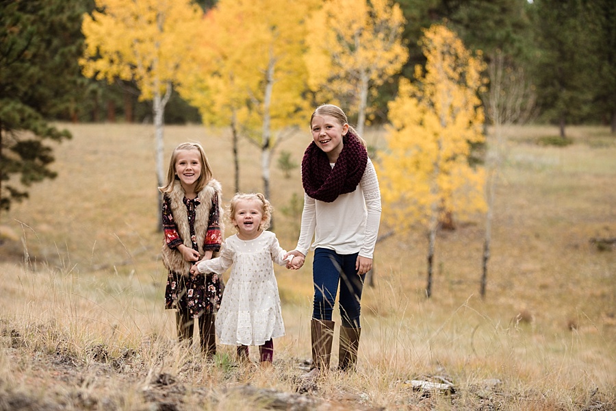 three sisters laughing in the mountains in fall in Colorado 