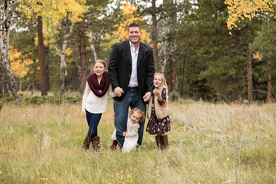 father poses with his three daughters in the fall in the Colorado mountains