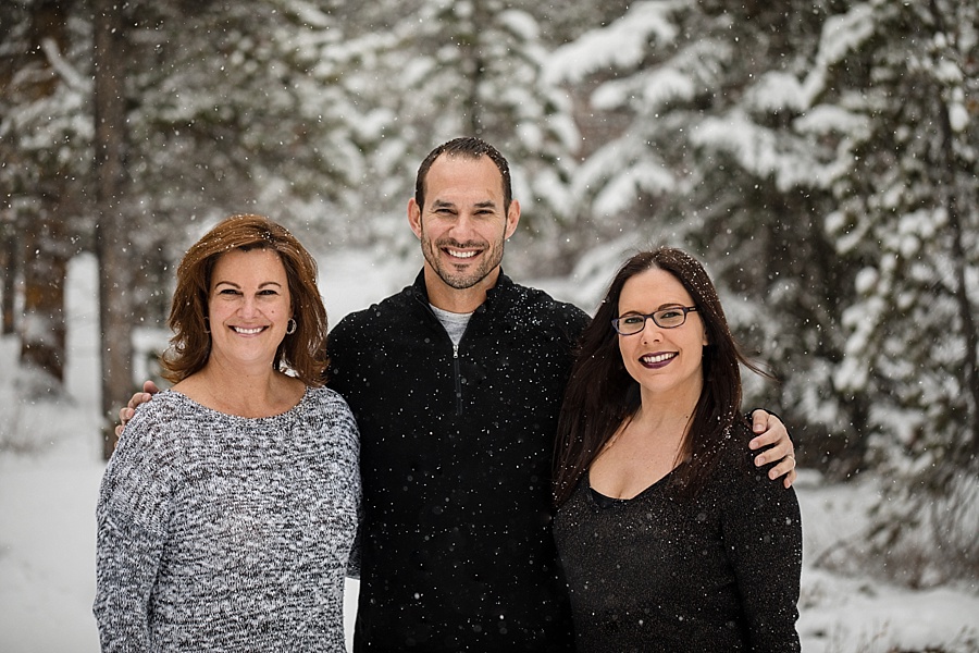 brother poses with his two sisters in the snow in Breckenridge 